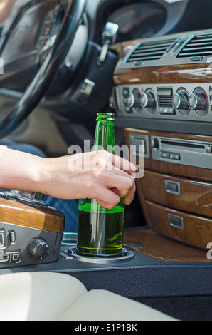 Driving Under the Influence. Female hand with bottle of beer. Stock Photo