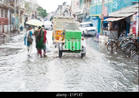 Defocussed view flash flood at Indian city street auto rickshaw bicycles and pedestrians after monsoon rain India Tamil Nadu Stock Photo