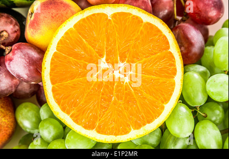 Fresh Orange on a background of different fruits and grapes Stock Photo