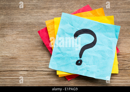 question mark on a sticky note against grained wood Stock Photo