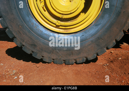 Wheel and tyre of enormous haulpak mining truck on red iron ore-containing earth, Pilbara region, Western Australia. No PR Stock Photo