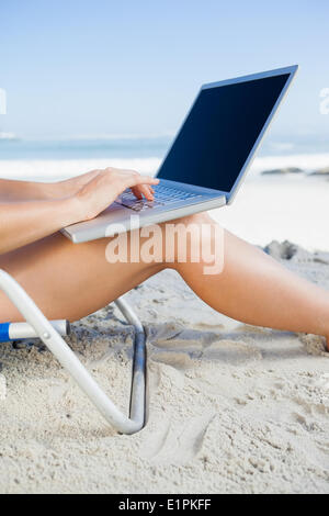 Woman sitting on beach using her laptop Stock Photo
