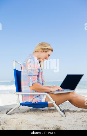 Woman sitting on beach using her laptop Stock Photo