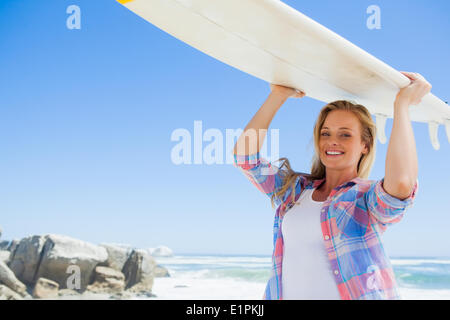 Blonde surfer holding her board smiling at camera Stock Photo