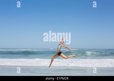 Fit woman jumping gracefully on the beach Stock Photo