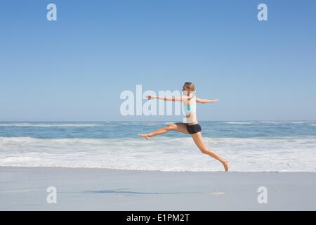 Fit woman jumping gracefully on the beach Stock Photo