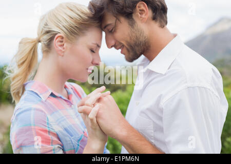 Cute affectionate couple standing outside holding hands Stock Photo