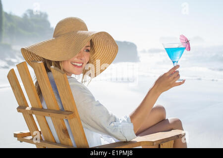 Woman relaxing in deck chair by the sea holding cocktail Stock Photo