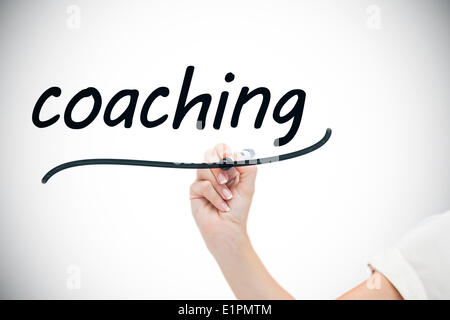 Businesswoman writing the word coaching Stock Photo