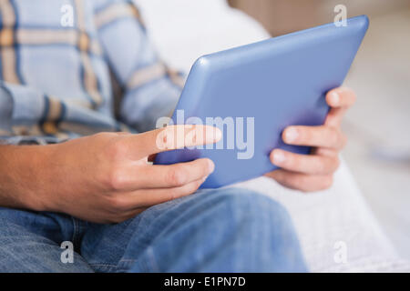 Man lying on couch using tablet pc Stock Photo