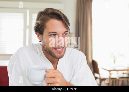 Handsome man having breakfast in his bathrobe drinking coffee Stock Photo