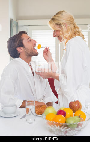 Cute couple in bathrobes having breakfast together Stock Photo