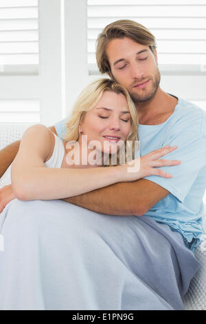 Cute casual couple sitting on couch under blanket Stock Photo