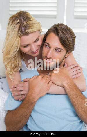 Happy casual couple hugging on couch Stock Photo