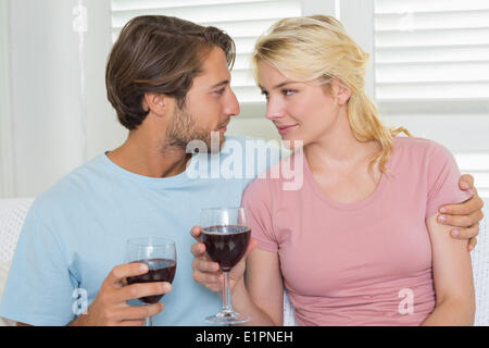 Happy couple drinking red wine together on the couch Stock Photo