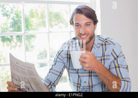 Casual smiling man having coffee while reading newspaper Stock Photo
