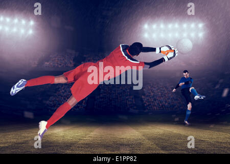 Composite image of goalkeeper in red making a save Stock Photo