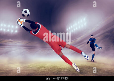 Composite image of goalkeeper in red making a save Stock Photo