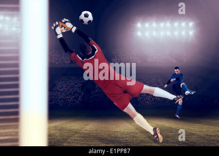 Composite image of goalkeeper in red jumping up Stock Photo