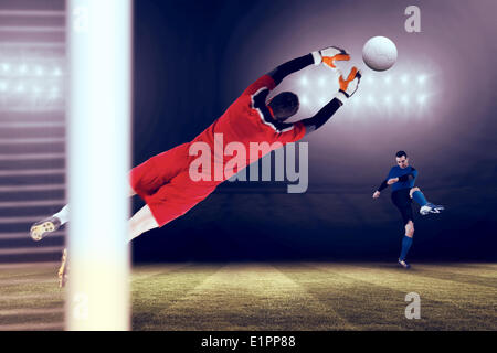 Composite image of goalkeeper in red jumping up Stock Photo