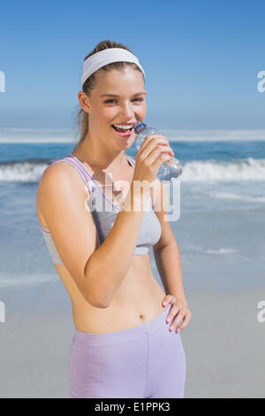 Sporty happy blonde drinking water on the beach Stock Photo