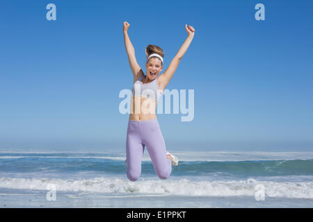 Sporty happy blonde jumping on the beach Stock Photo