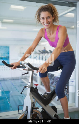 Pretty fit woman on the spin bike smiling at camera Stock Photo