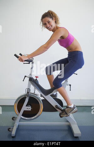 Fit woman on the spin bike smiling at camera Stock Photo