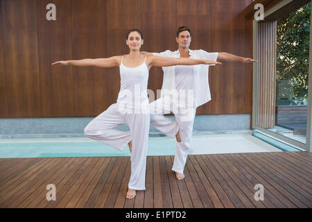 Peaceful couple in white doing yoga together in tree position Stock Photo