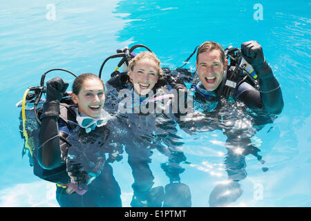 Smiling friends on scuba training in swimming pool cheering at camera Stock Photo