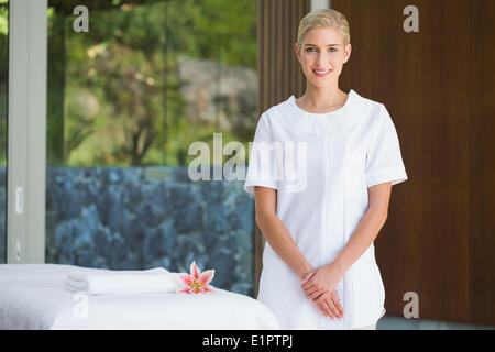 Smiling beauty therapist standing beside massage towel Stock Photo