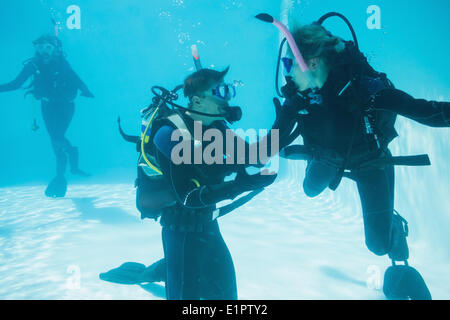 Friends on scuba training submerged in swimming pool Stock Photo