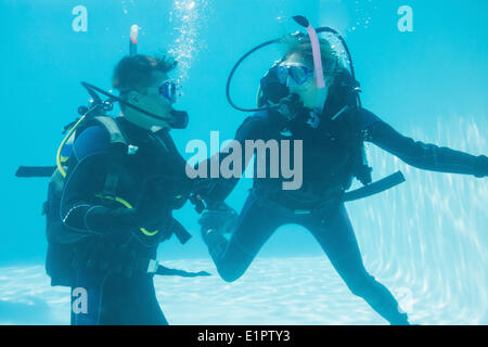 Friends on scuba training submerged in swimming pool Stock Photo