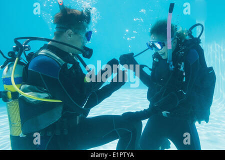 Man proposing marriage to his shocked girlfriend underwater in scuba gear Stock Photo