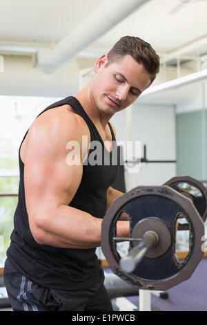 Muscular bodybuilder lifting heavy black barbell weight Stock Photo