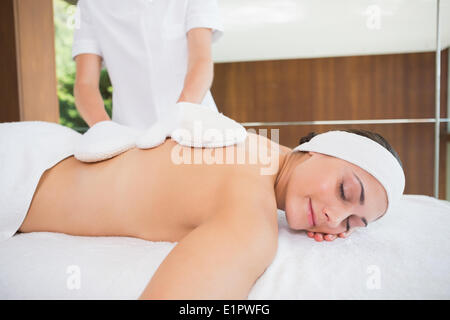 Beauty therapist rubbing womans back with heated mitts Stock Photo