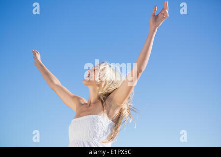 Woman in white dress standing with arms outstretched Stock Photo