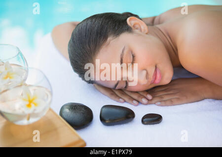 Smiling brunette lying on towel having a hot stone massage Stock Photo