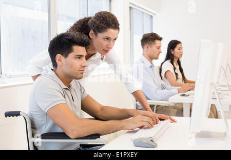 Casual businesswoman helping colleague in wheelchair Stock Photo