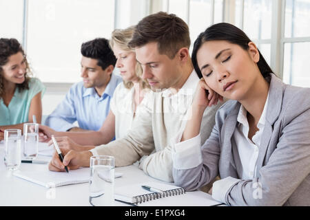Casual businesswoman falling asleep during meeting Stock Photo