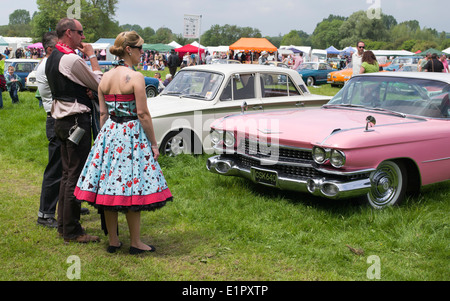 People dressed up at a Nostalgic and vintage show looking at a pink Cadillac. England Stock Photo