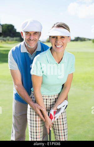 Golfing couple putting ball together smiling at camera Stock Photo