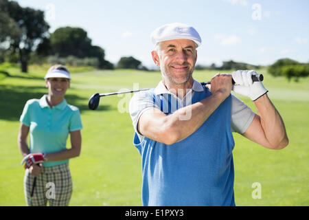 Happy golfer teeing off with partner behind him Stock Photo