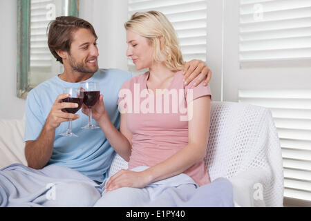 Happy couple sitting on couch with red wine Stock Photo