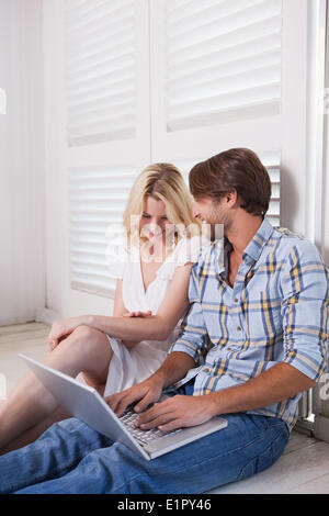 Young couple sitting on floor using laptop Stock Photo