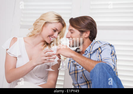 Young couple sitting on floor drinking wine Stock Photo