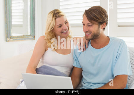 Young couple sitting on the couch together using laptop Stock Photo