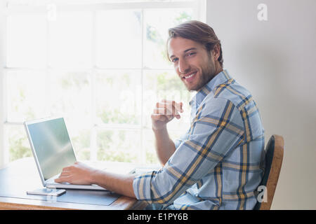 Handsome man sitting at table using laptop Stock Photo