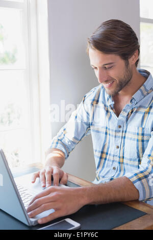 Handsome man sitting at table using laptop Stock Photo