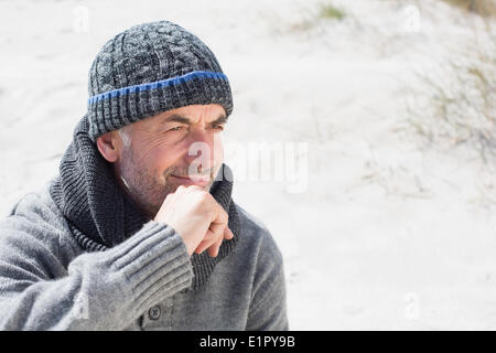 Attractive man smiling on the beach in hat and scarf Stock Photo